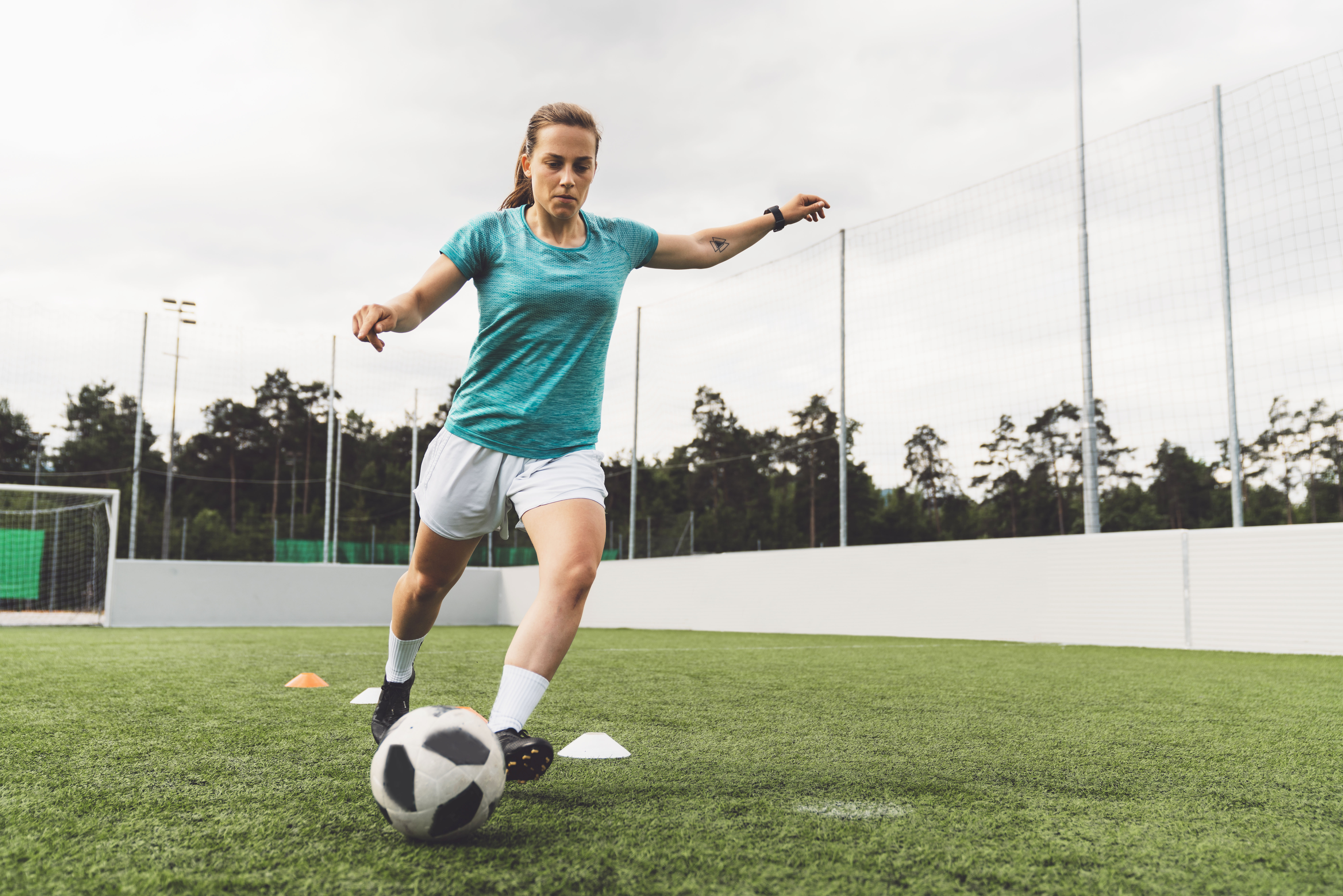 Jonge voetbalster tijdens de training met bal aan voet