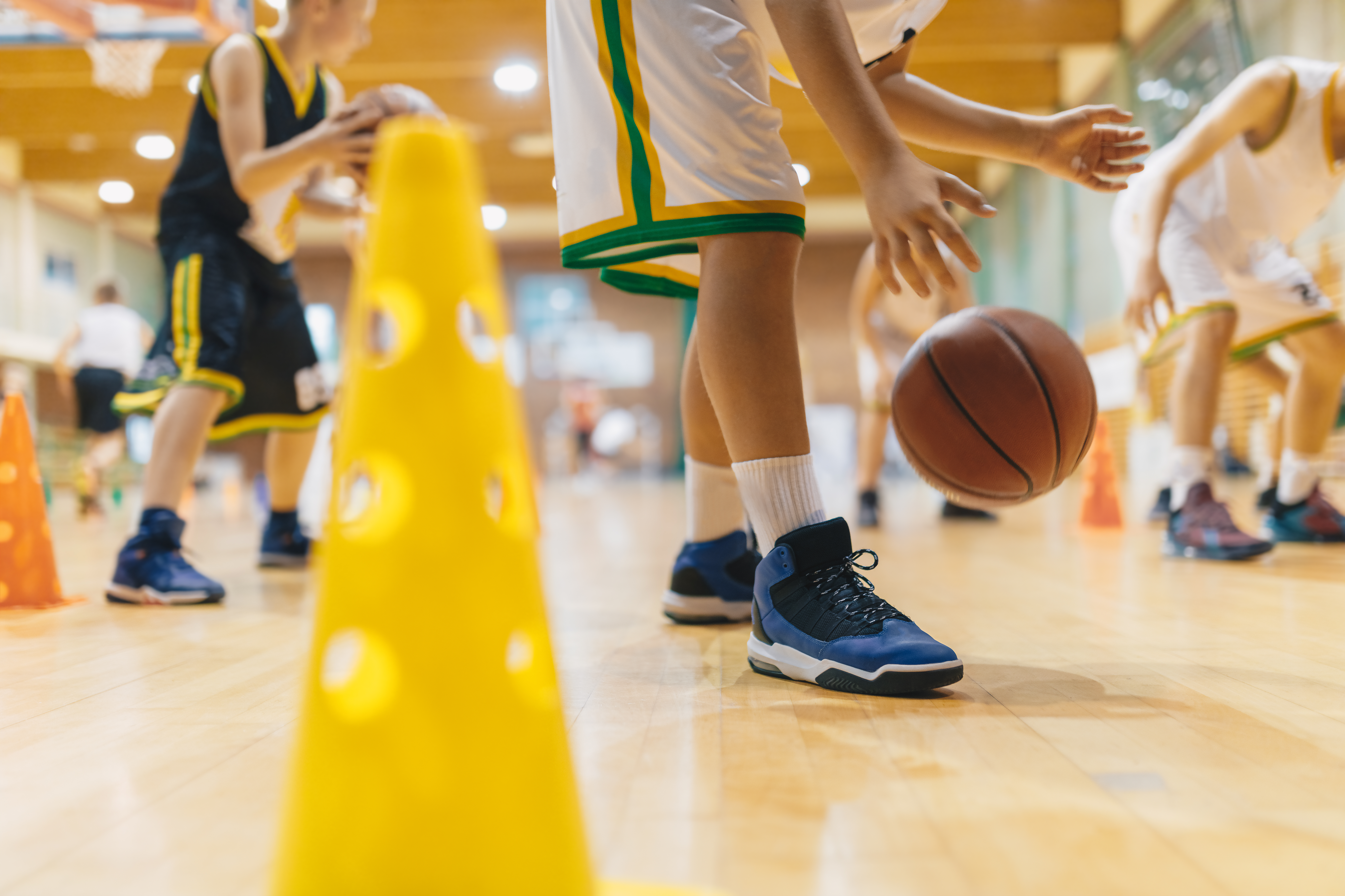 Jonge basketters dribbelen met de bal tijdens de training 