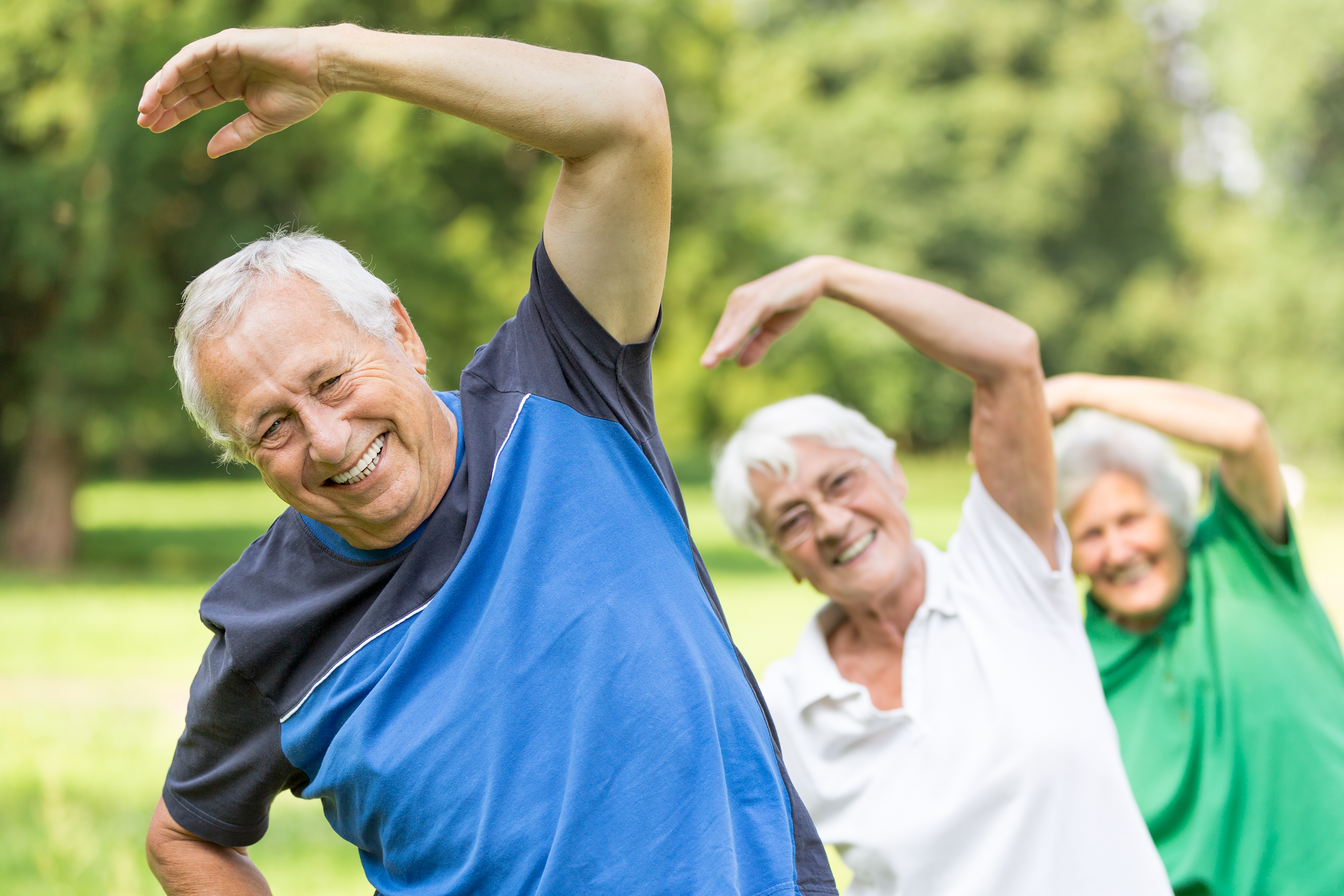 Drie senioren doen aan gymnastiek in het park