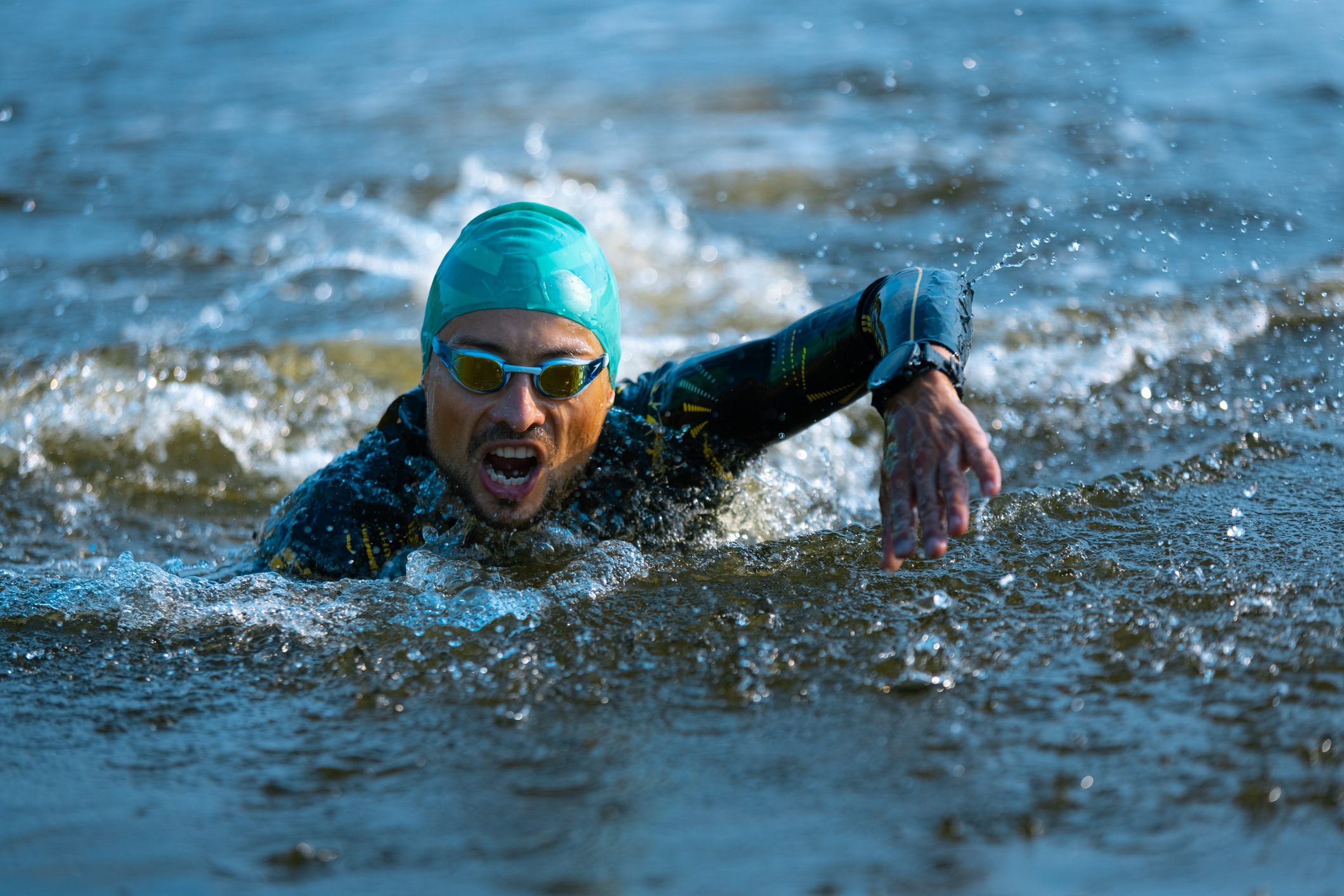 Professional triathlete swimming in river's open water. Man wearing swim equipment practicing triathlon on the beach in summer's day. Concept of healthy lifestyle, sport, action, motion and movement.