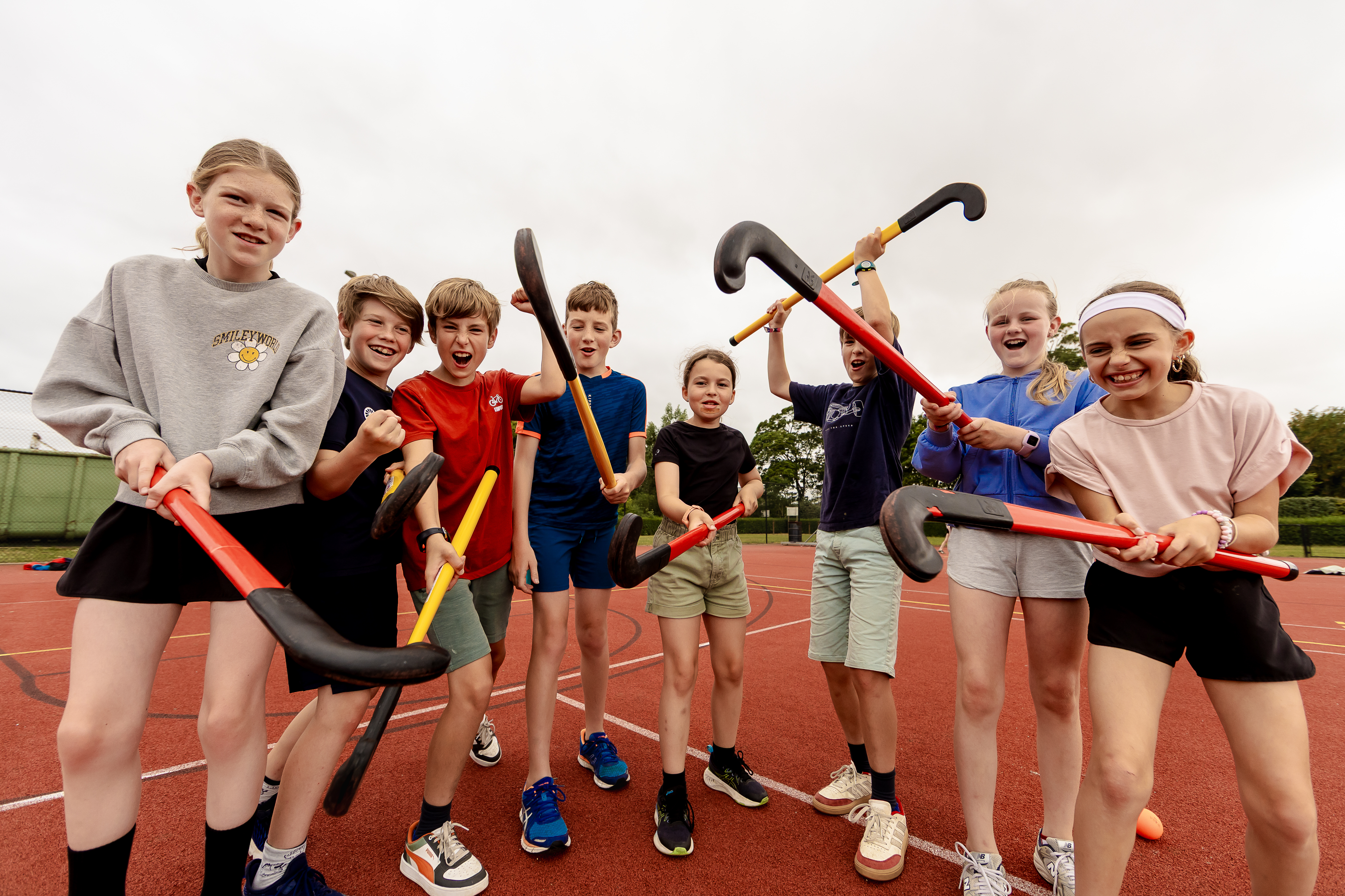 groep jongeren met hockeysticks