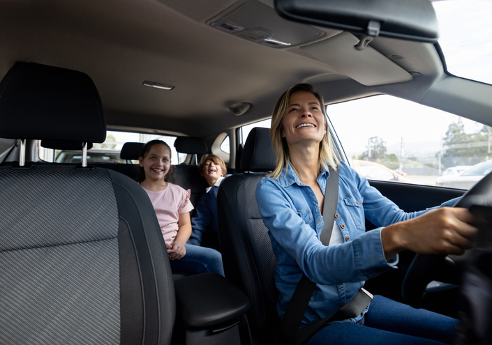 Happy Latin American mother driving her kids in the back seat of her car -Transportation concept