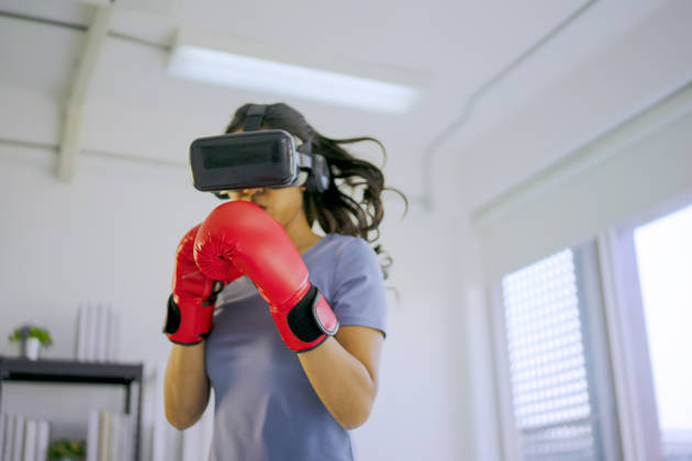 Young woman is exercise with virtual reality glasses. She is boxer. Active solo daily life and technology concept.