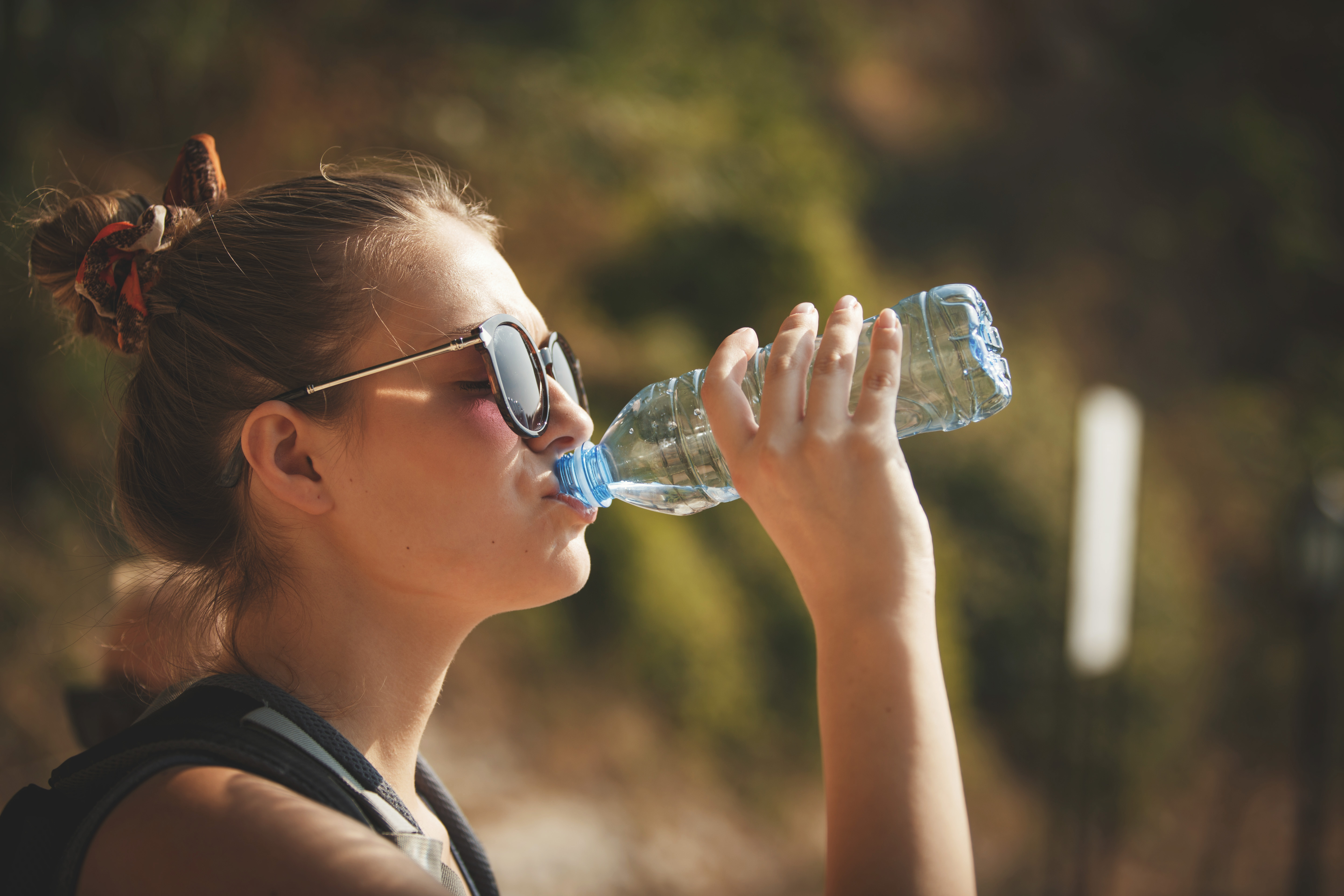 Zij-aanzicht van vrouw die flesjes water drinkt