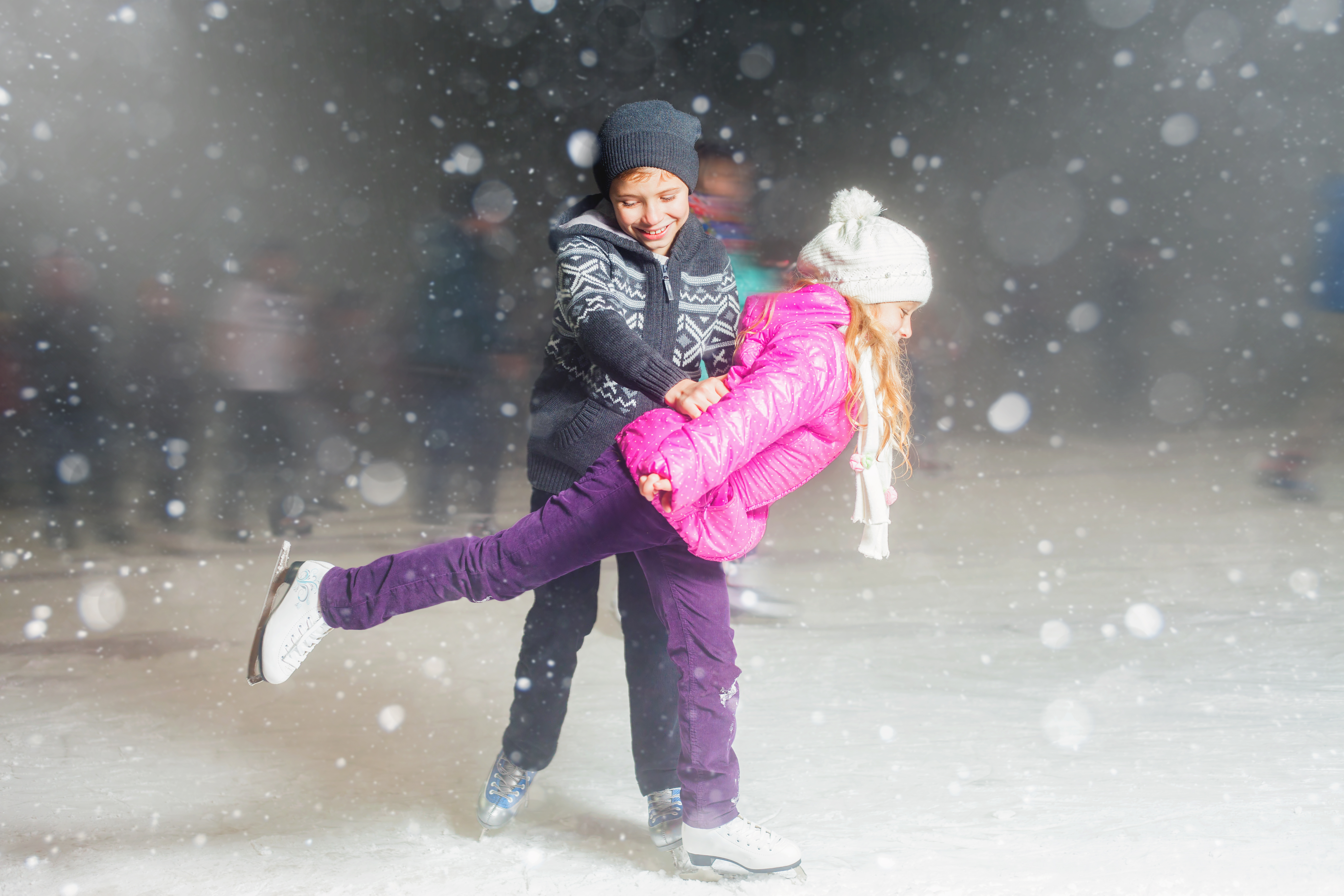 Happy children ice skating at ice rink outdoor, figure skating, at winter snowy night, sport and healthy lifestyle, ice skating at Holland. Funny kids, boy and girl, sister and brother. Family