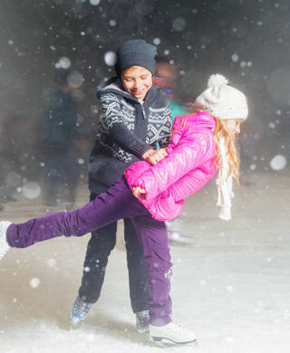 Happy children ice skating at ice rink outdoor, figure skating, at winter snowy night, sport and healthy lifestyle, ice skating at Holland. Funny kids, boy and girl, sister and brother. Family