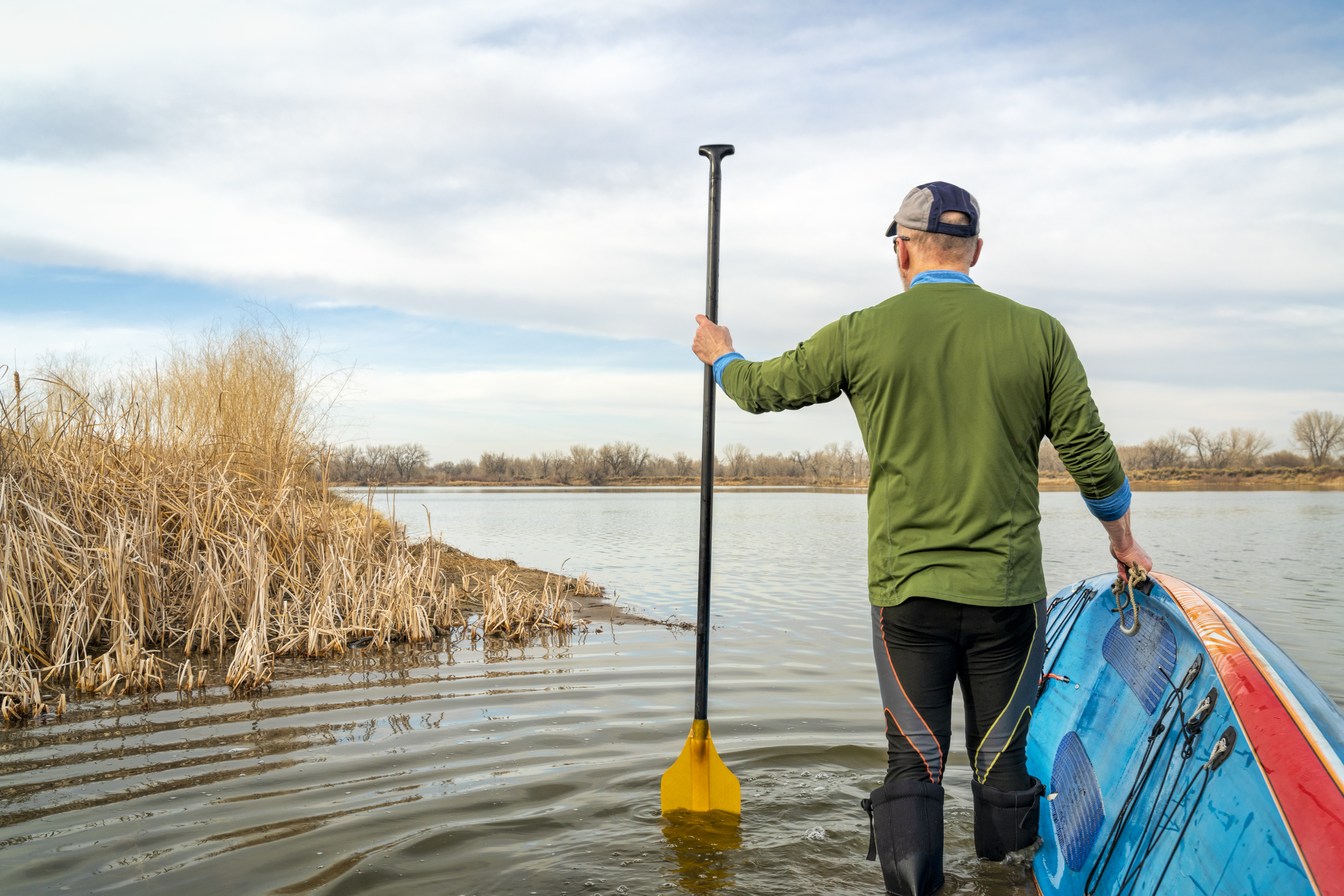 early spring stand up paddling, senior male with his paddleboard on lake in Colorado