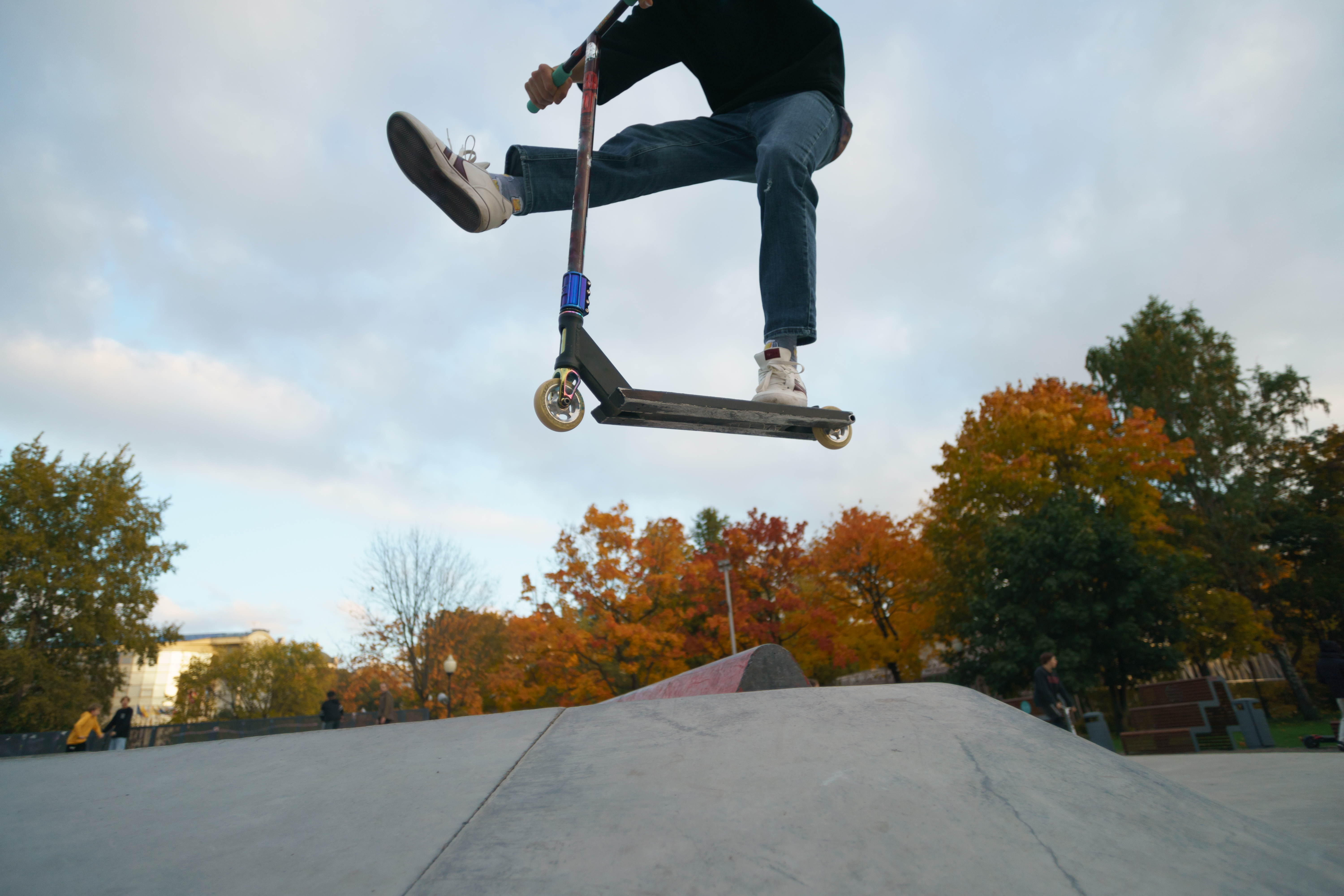 Teenager performs trick in the city skate  park. Push scooter. He is jumping. Extreme sports is popular among youth. View of park of body