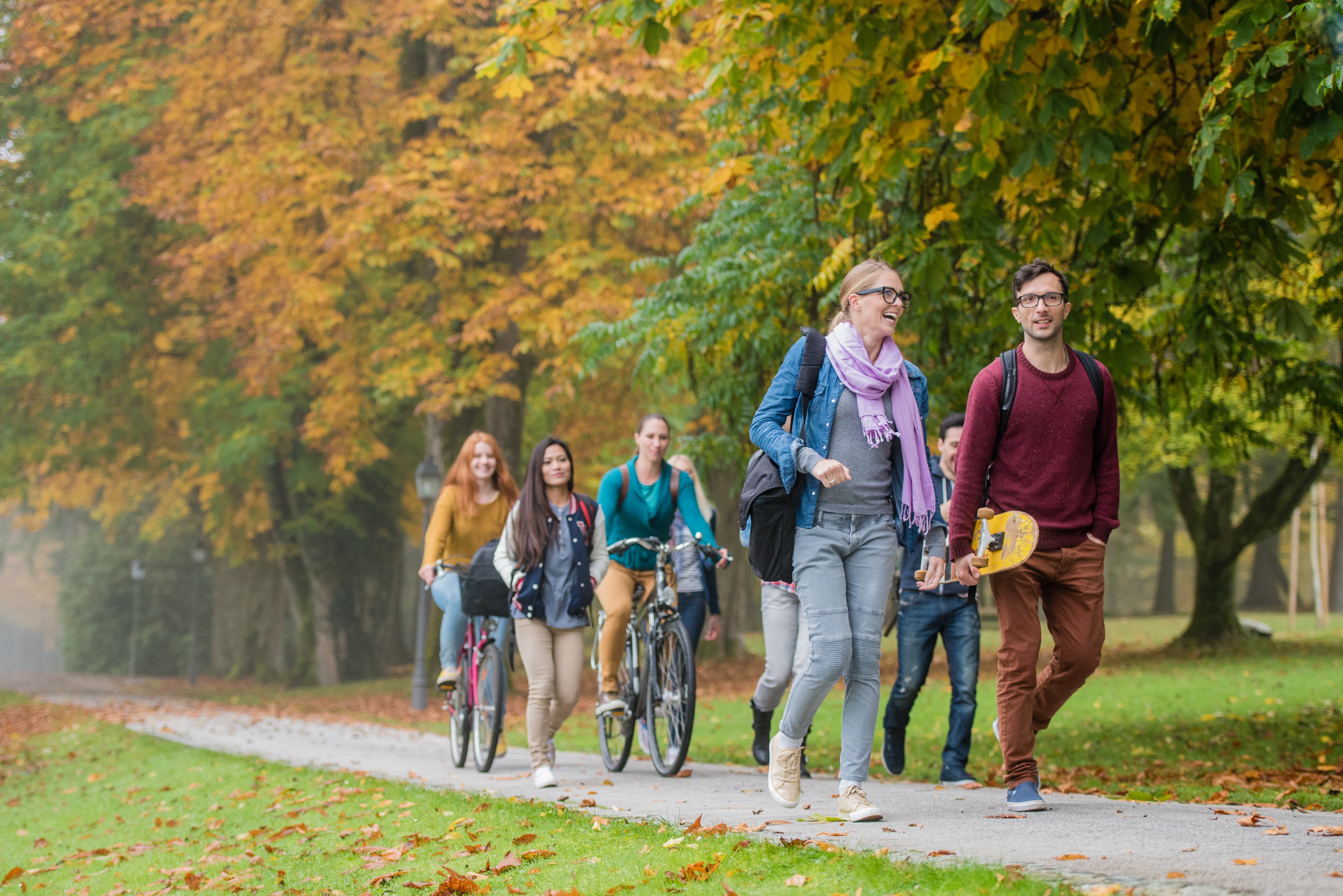 University students walking and cycling on footpath in campus.