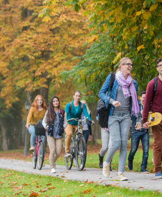 University students walking and cycling on footpath in campus.