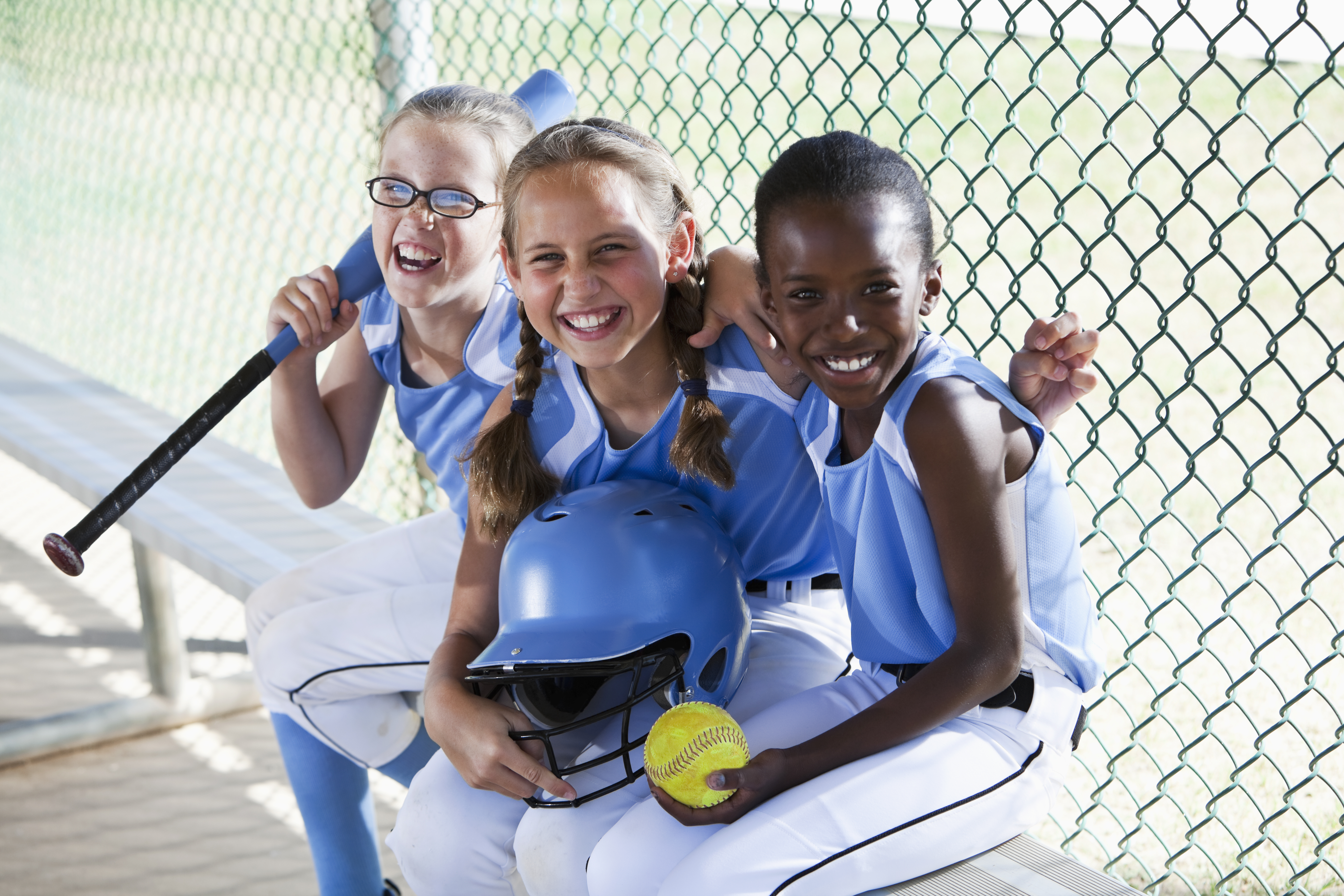 Multi culturele meisjes van baseballteam zitten in dug-out.