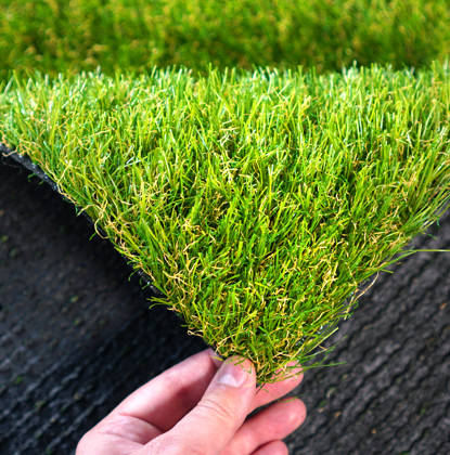 Hand houdt stukje kunstgras vast
